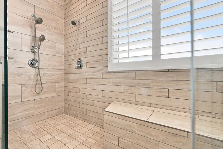 Walk-in shower with natural stone tile walls and flooring