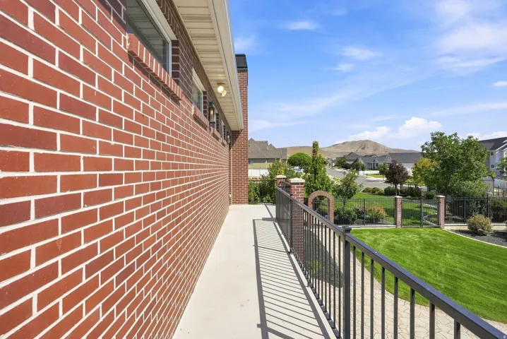 Brick exterior featuring a concrete walkway and black metal railing