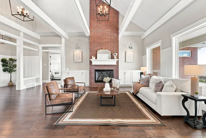 Vaulted ceilings with exposed beams complement the full-height brick fireplace featuring a white mantel