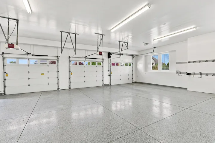 Three white overhead garage doors with upper window inserts