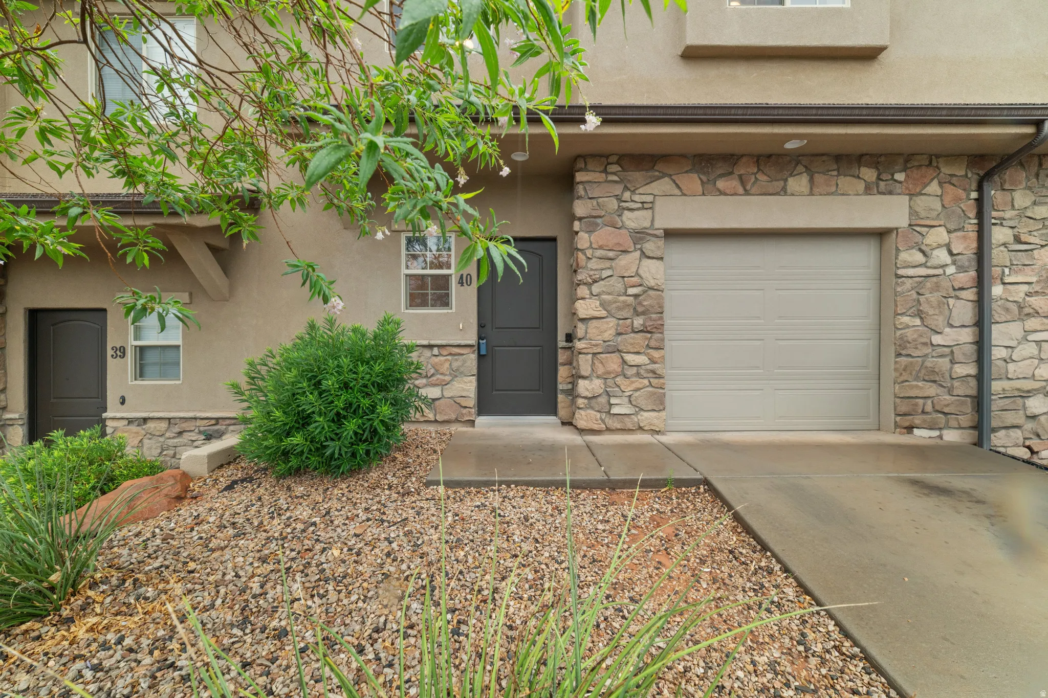 Exterior facade featuring stone veneer accents, stucco siding, and an attached single-car garage