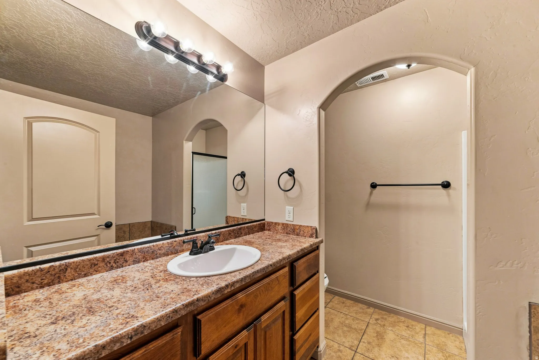 Bathroom vanity featuring a single basin sink, laminate countertop, and wood-finish cabinetry
