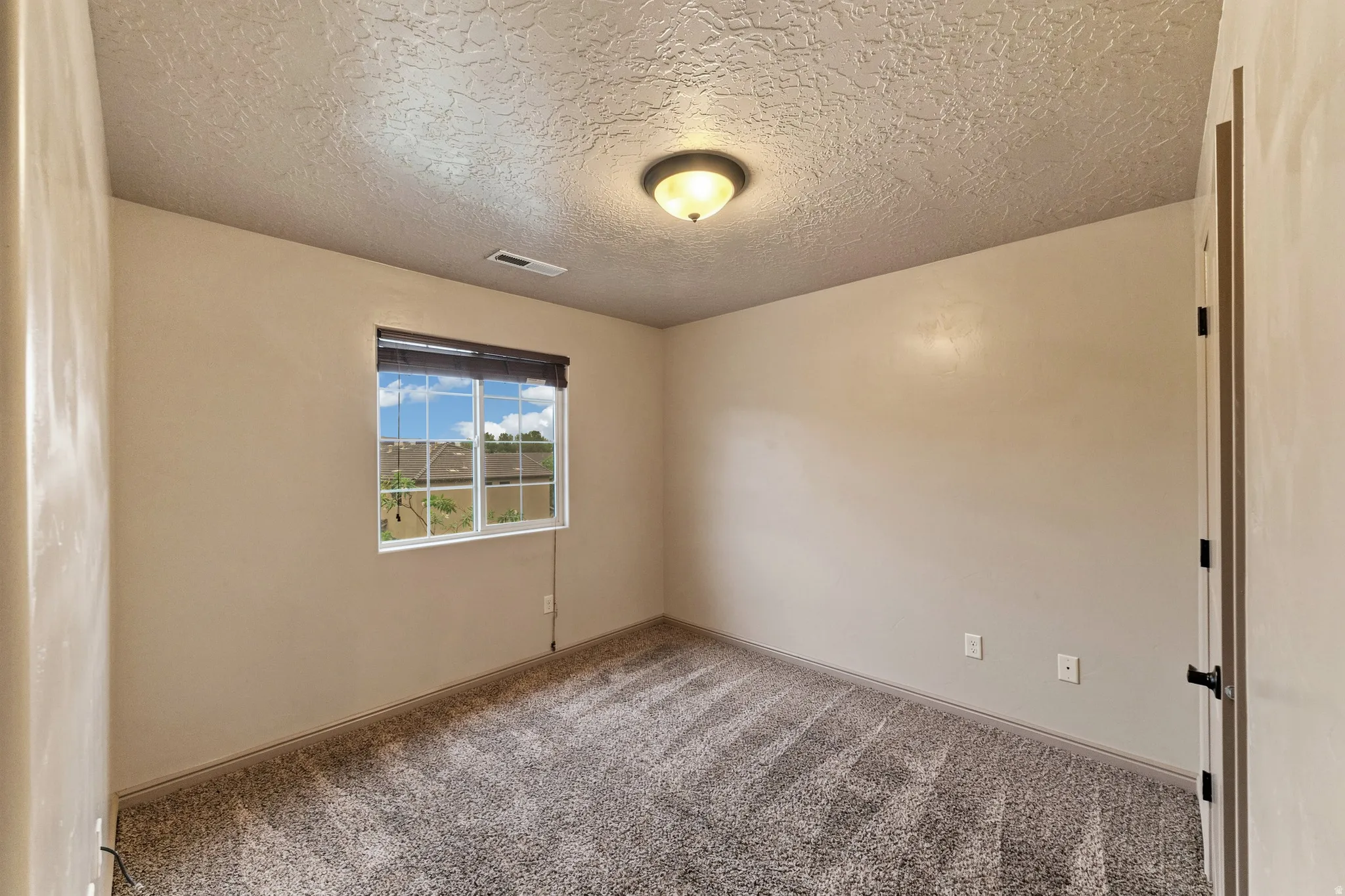 Neutral-toned wall finishes with a single window featuring a dark roller shade
