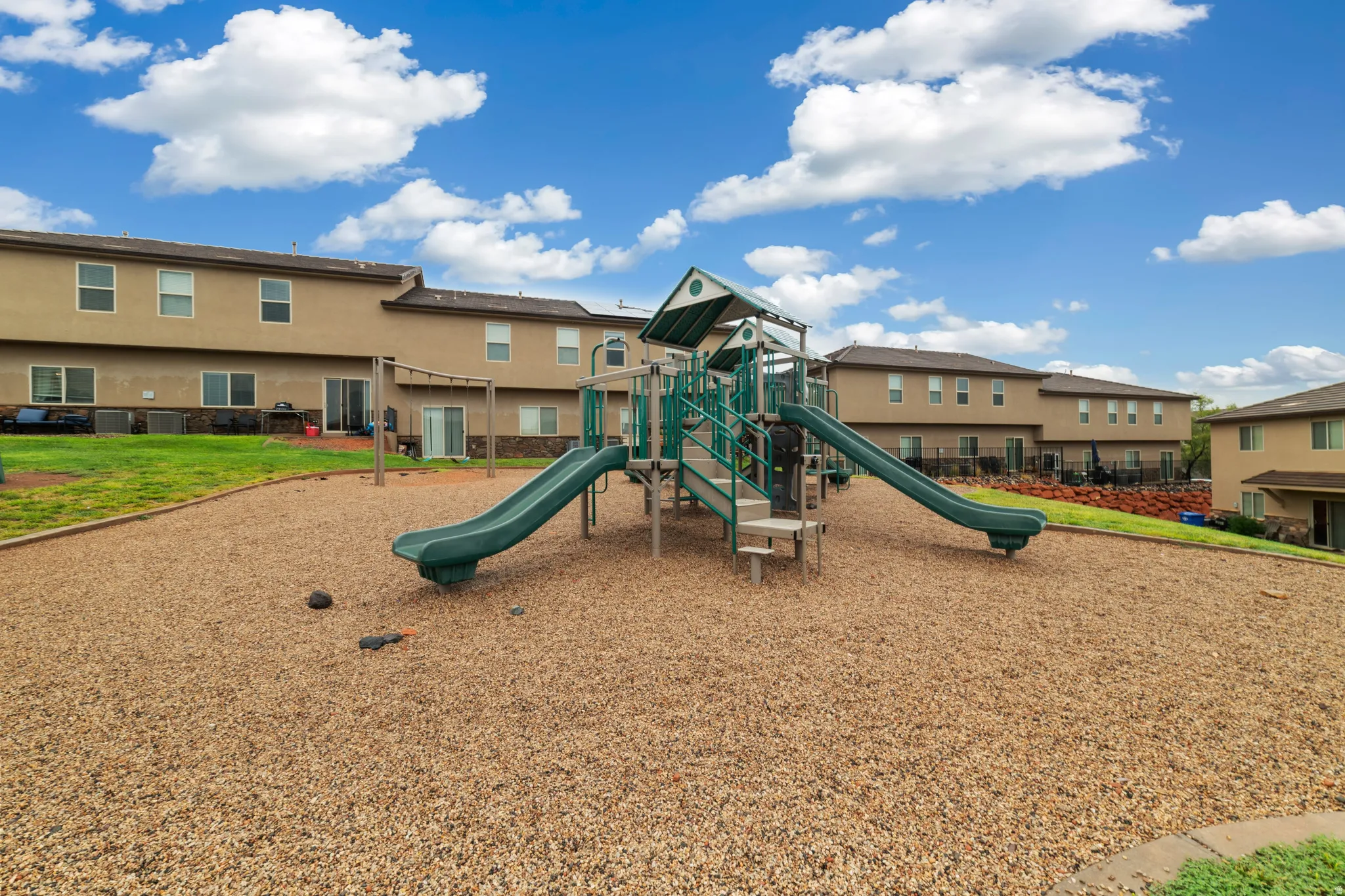 Outdoor play structure featuring multiple slides and climbing elements set on a wood chip surface