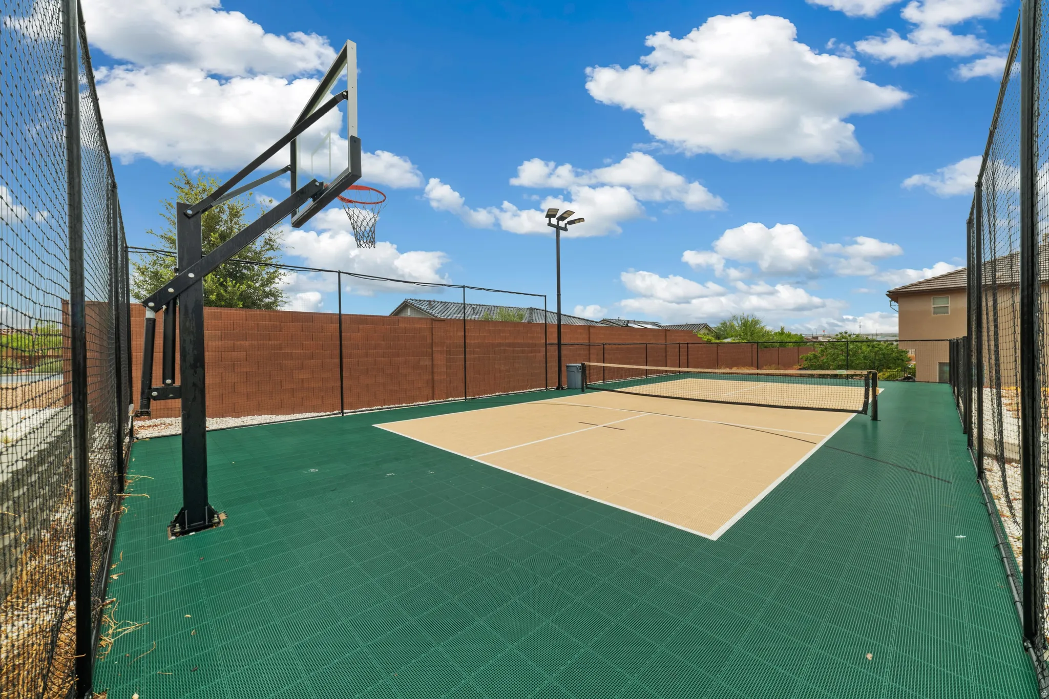 Multi-sport court featuring a basketball hoop and pickleball court with a net