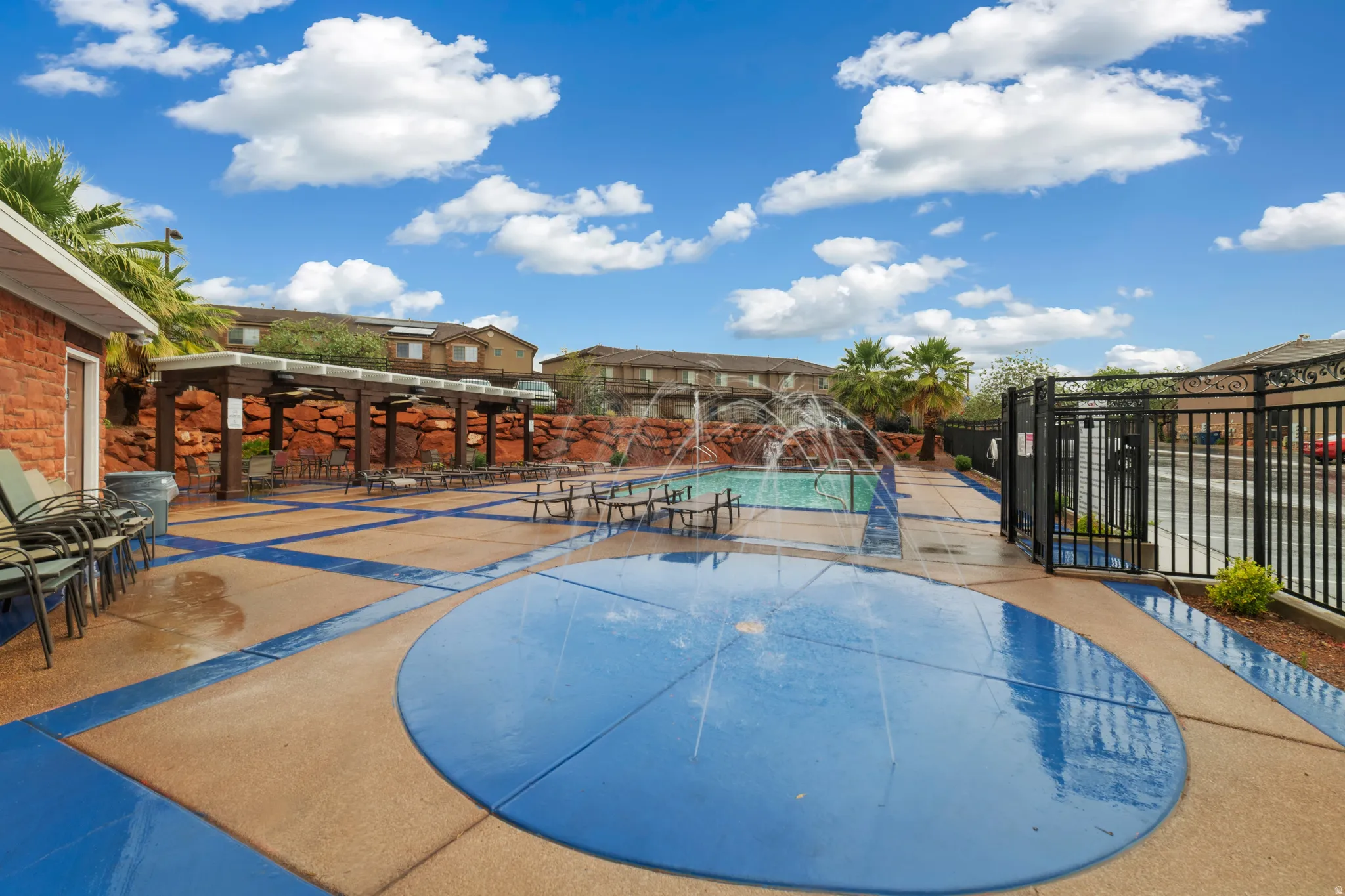 Recreational area featuring a splash pad, swimming pool with water features, and an expansive patio with shade structures