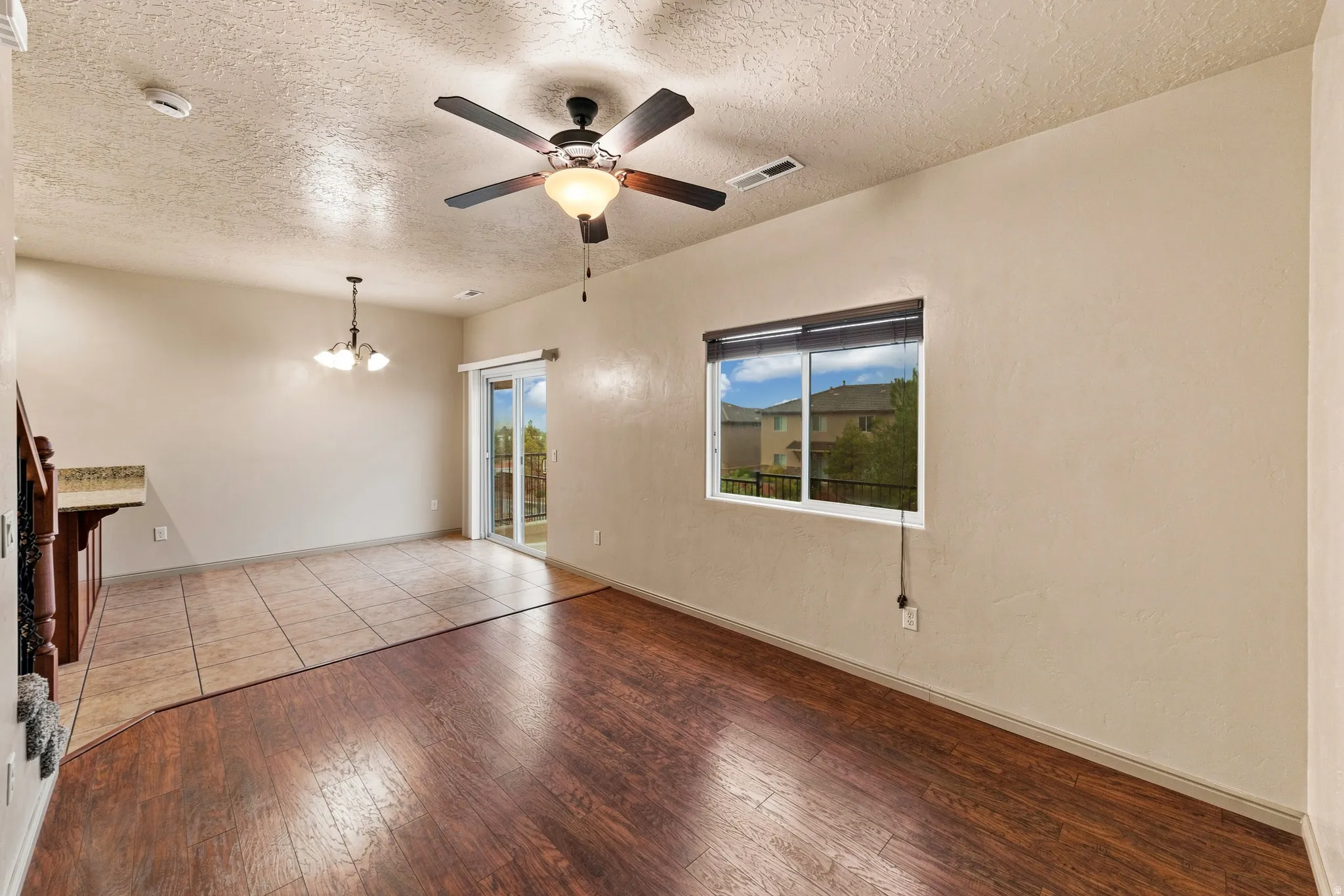 Open-concept living space featuring wood-finish flooring, a ceiling fan with integrated lighting, and a sliding glass door leading to an outdoor area