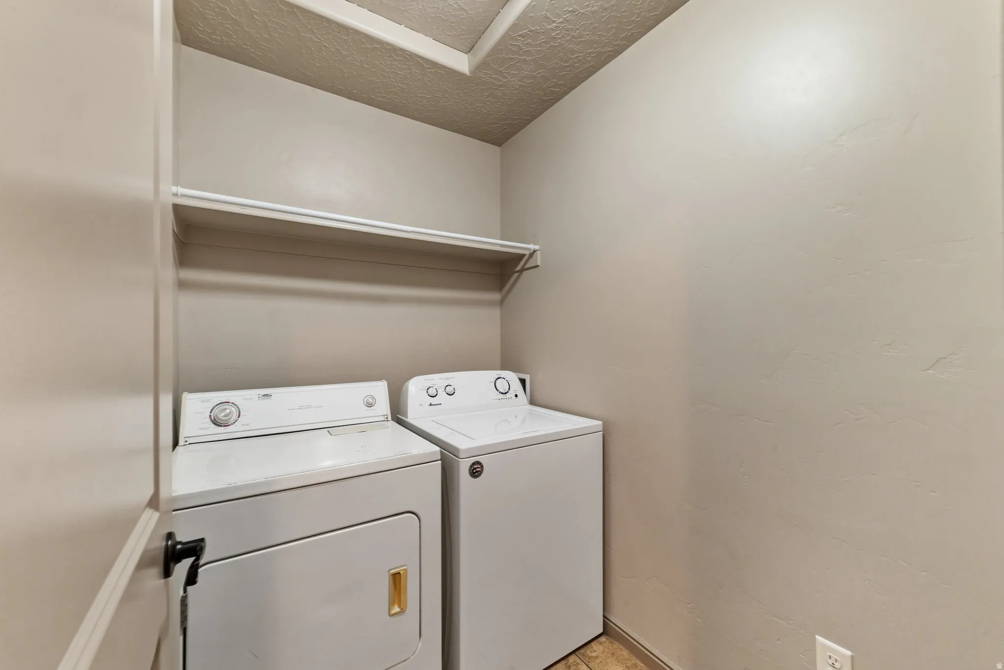 Dedicated laundry area with upper shelving and neutral wall tones