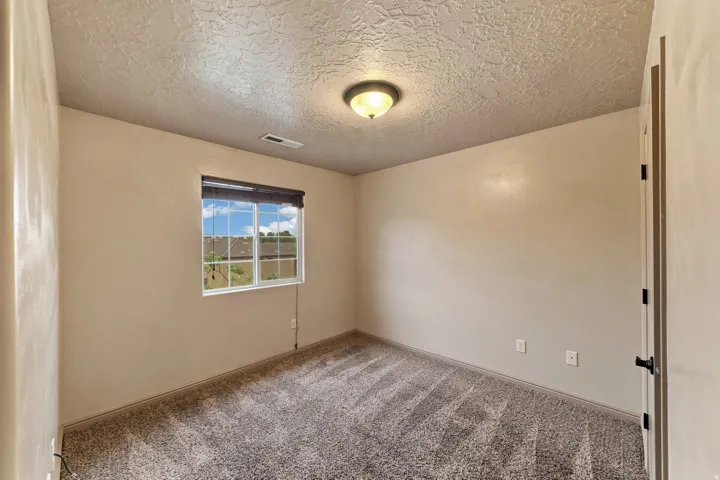 Neutral-toned wall finishes with a single window featuring a dark roller shade