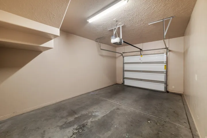 Single-bay garage with a concrete floor, automatic garage door opener, and overhead fluorescent lighting