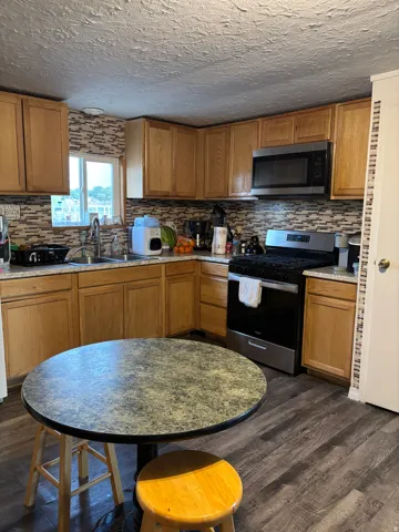 Kitchen featuring wood-finish flooring, a mosaic tile backsplash, and light wood cabinetry