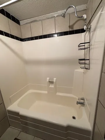 Bathtub and shower combination featuring a chrome finish shower head and faucet