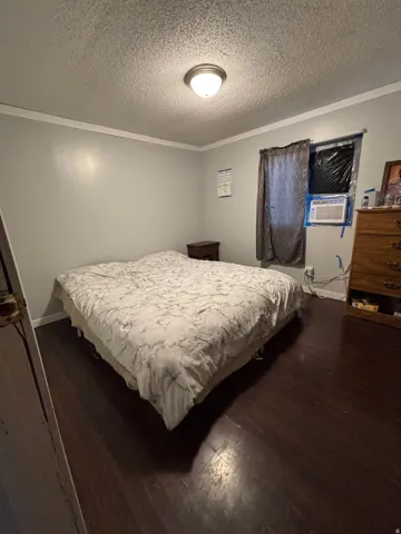 Bedroom featuring dark wood-finish flooring, light gray wall paint, and white crown molding