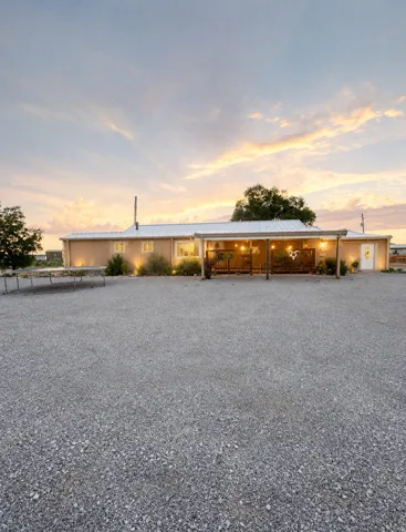Stucco exterior with a covered porch, string lighting, recessed lighting, and a metal roof