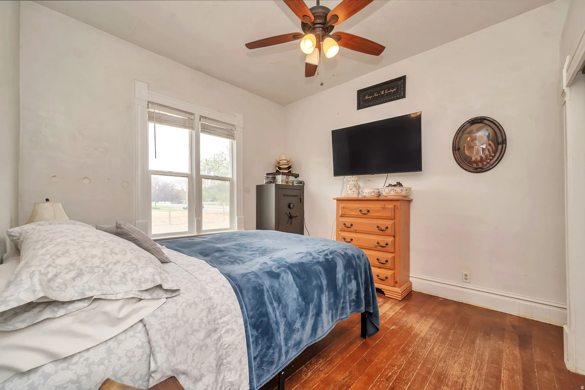 Room featuring wood-finish flooring, a ceiling fan with integrated lighting, and a double window with blinds