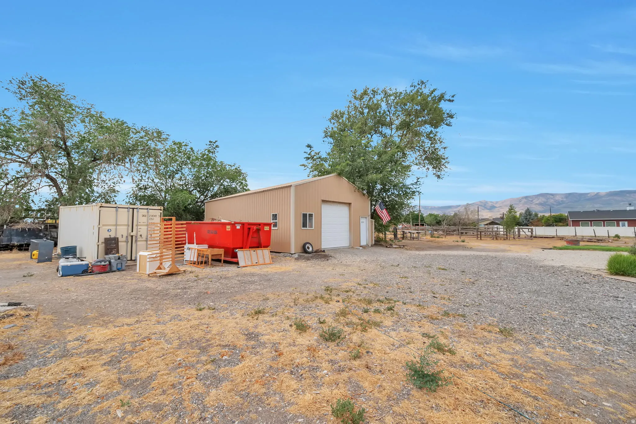 Gravel lot featuring a detached metal building with a roll-up garage door and side entry door