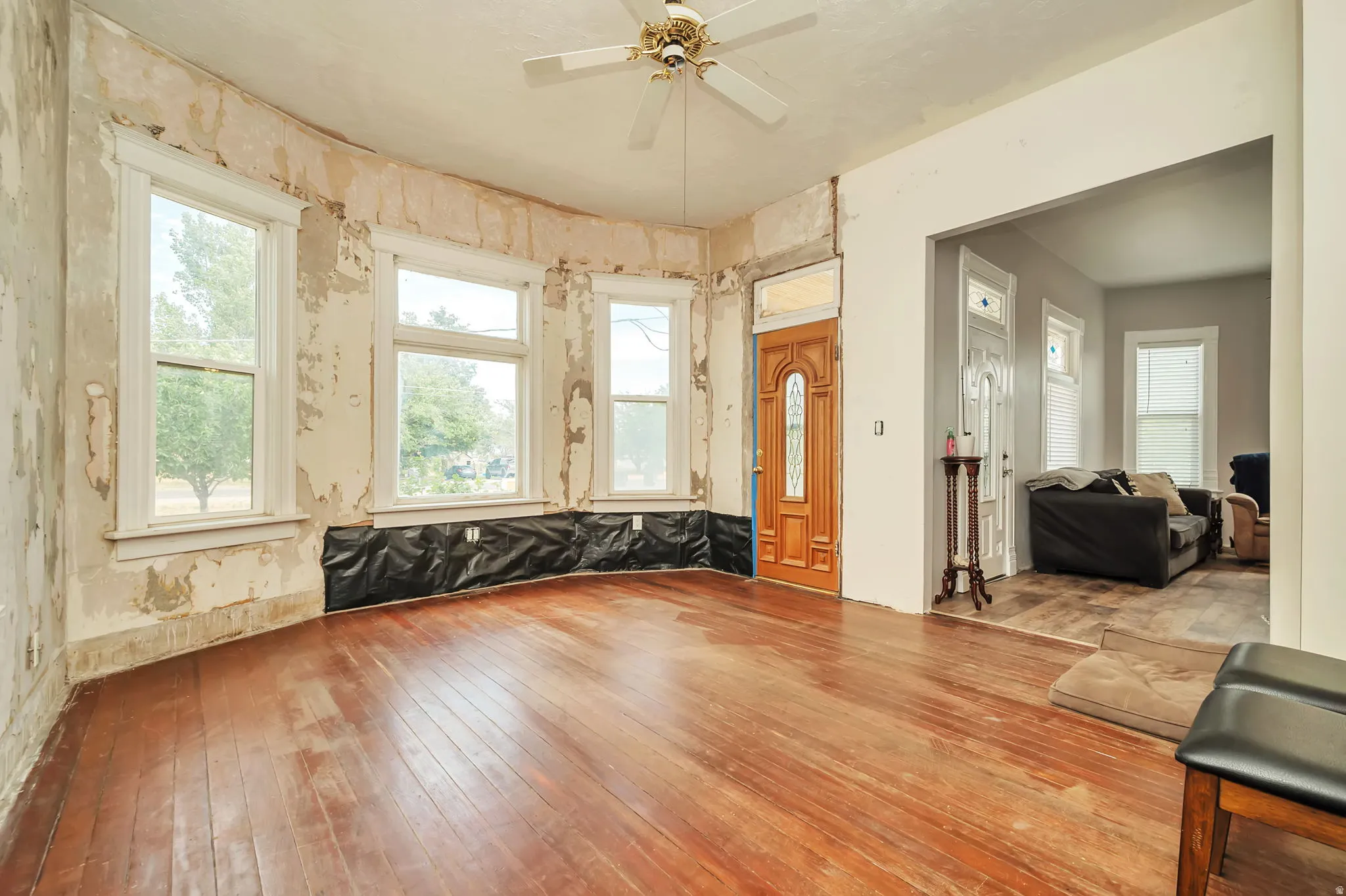 Spacious room featuring wood-finish flooring, a bay window configuration with multiple windows, and a panel-style entry door
