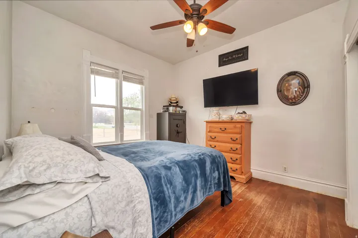 Room featuring wood-finish flooring, a ceiling fan with integrated lighting, and a double window with blinds