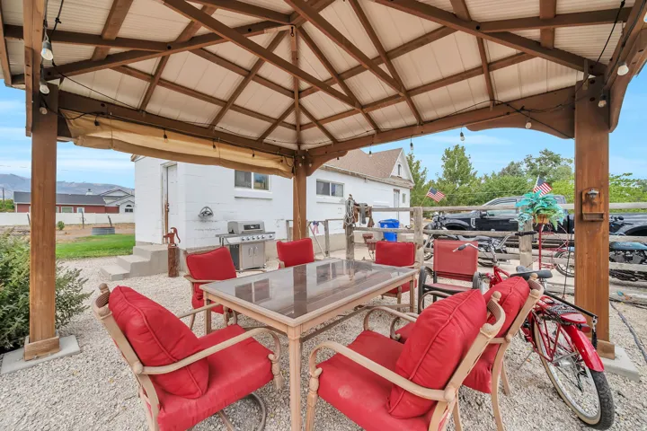 Outdoor gazebo with a wood frame and metal roof, featuring string lighting