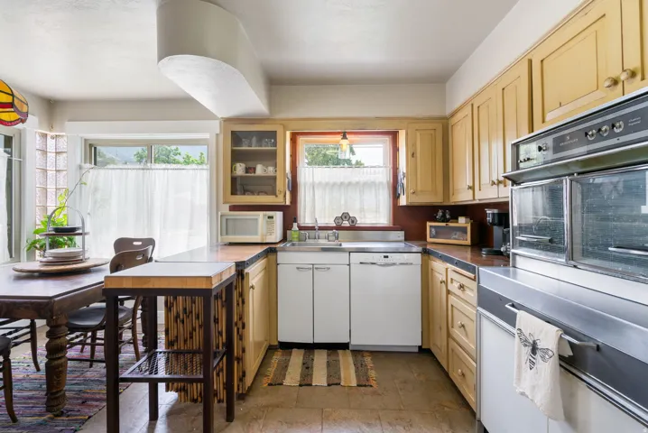 U-shaped kitchen featuring wood cabinetry, integrated vintage double wall ovens, a stainless steel sink, and a dishwasher