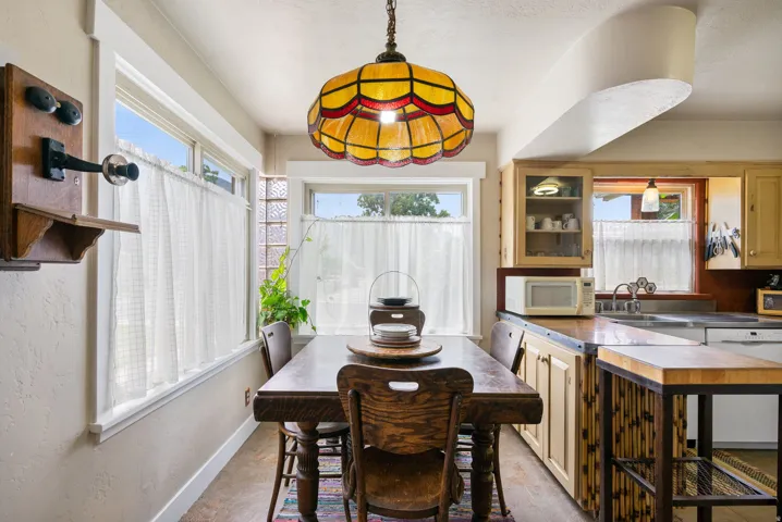 Dining area featuring a decorative stained glass pendant light fixture, wood-finish flooring, and multiple windows