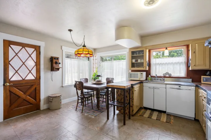 Kitchen space featuring tile flooring, a dark wood dining table, and a stained wood door with diamond-patterned glass inserts
