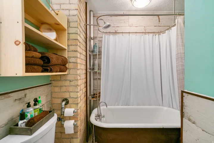Clawfoot bathtub with an overhead shower and white shower curtain