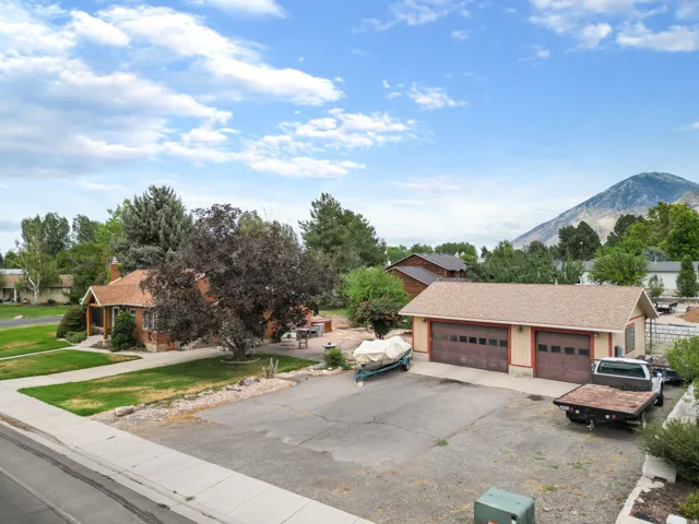 Expansive paved driveway leading to a detached garage with two bay doors, offering substantial parking