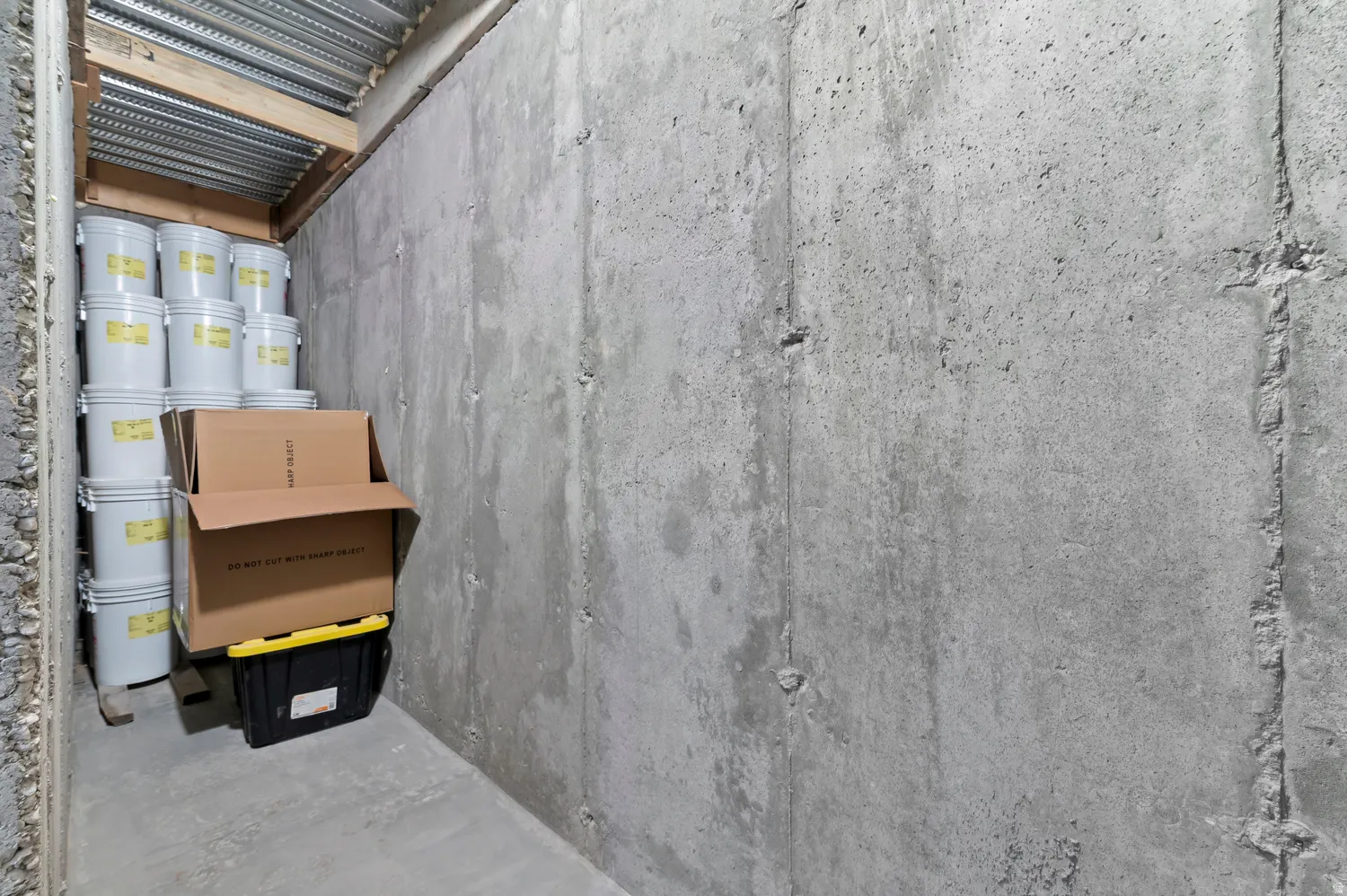 Storage area featuring concrete walls and a corrugated metal ceiling