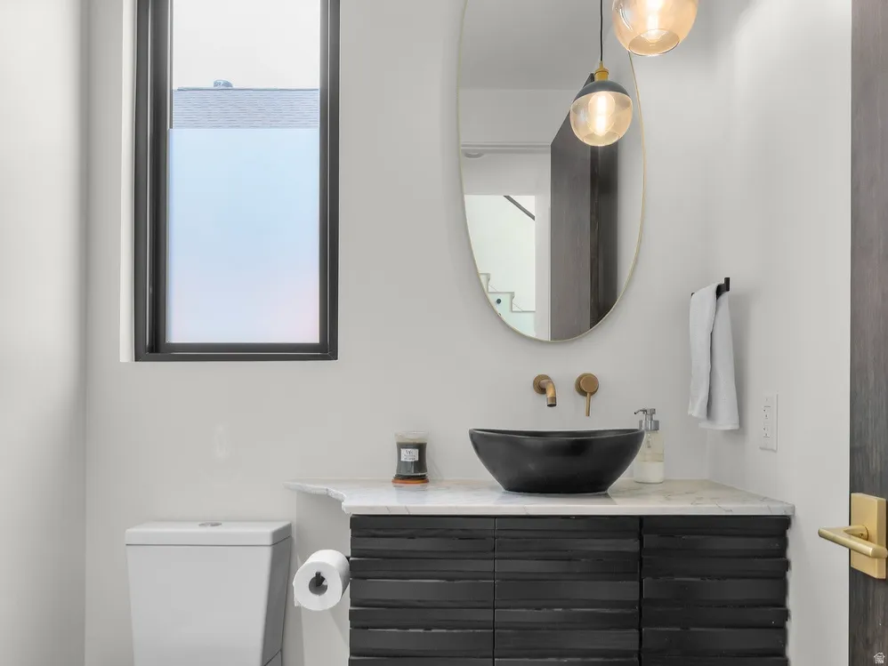 Modern powder room featuring a black textured vanity with a white countertop and a vessel sink