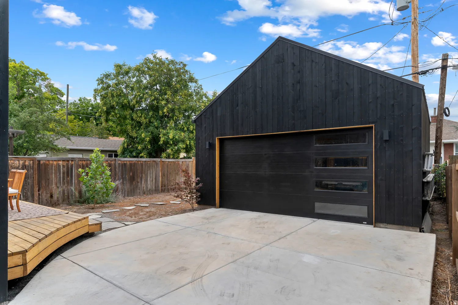 Modern black vertical siding structure with an attached garage featuring a dark wood-finish door with horizontal window inserts