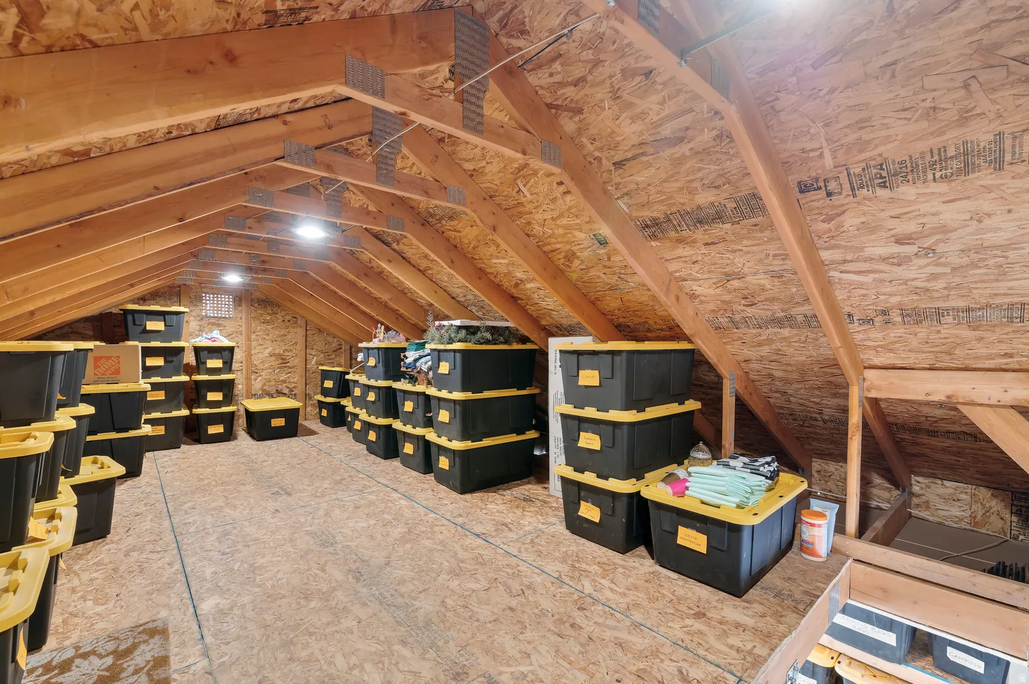 Storage above garage. Spacious attic storage area featuring exposed wood beams and oriented strand board walls