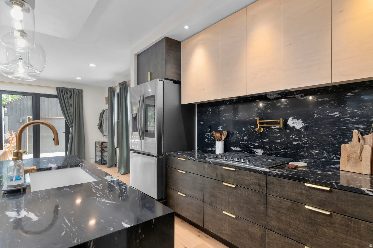 Contemporary kitchen featuring dark countertops with white veining, light wood-finish upper cabinetry, and dark wood-finish lower cabinetry