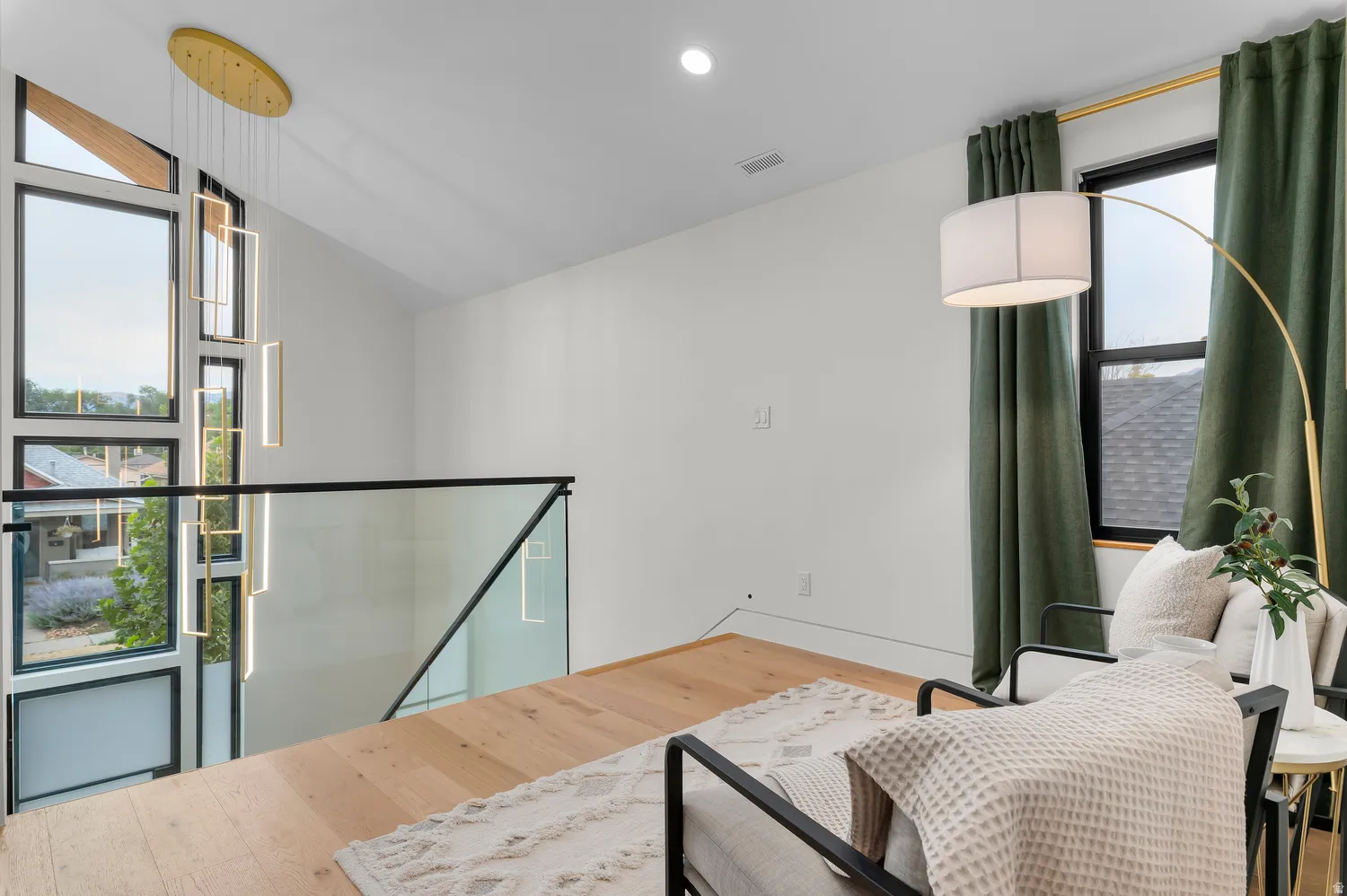 Contemporary living area featuring wood-finish flooring and a minimalist glass railing