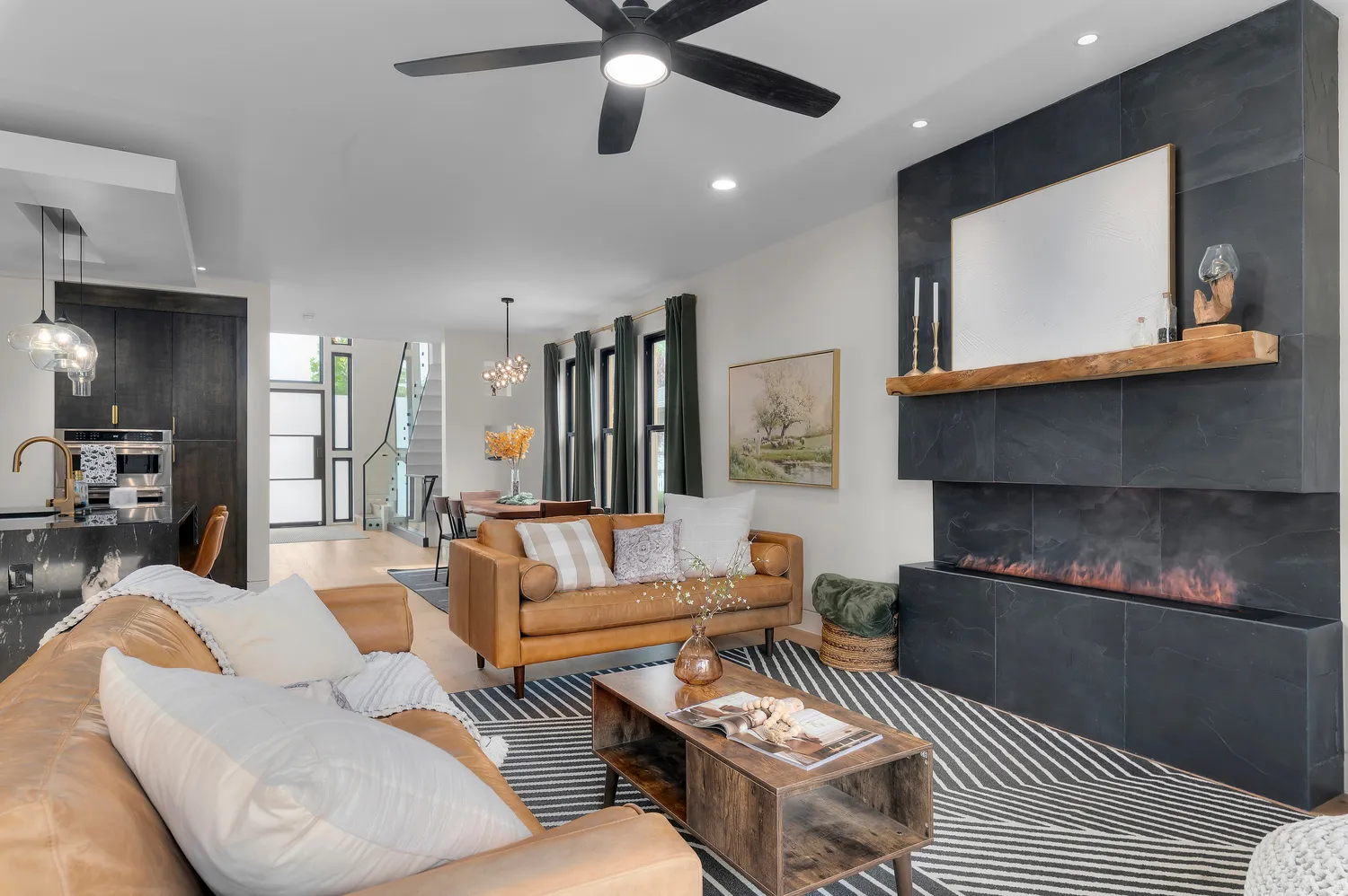 Open-concept living area featuring a modern fireplace with a dark tile surround and a wood mantel