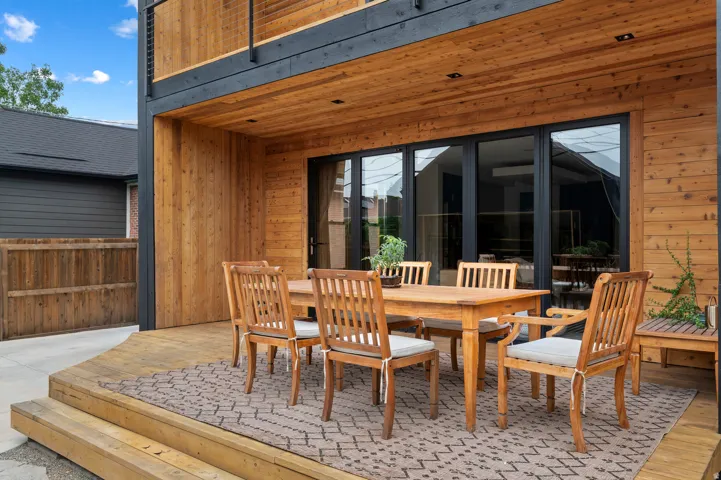 Expansive wooden deck featuring multiple steps, a built-in wooden bench, and a privacy fence
