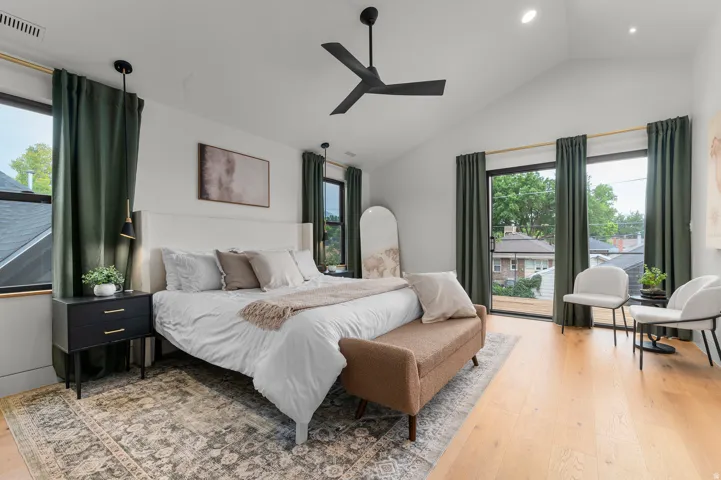 Vaulted ceiling bedroom featuring light wood-finish flooring and ample natural light from multiple windows
