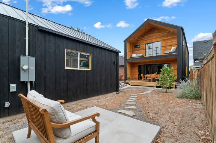 Contemporary architectural design featuring a two-story structure with a peaked roofline, wood-finish siding, and black exterior accents