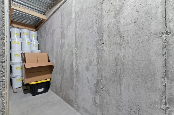 Storage area featuring concrete walls and a corrugated metal ceiling