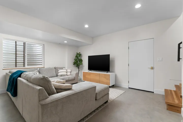 Spacious living area featuring light-colored walls and recessed lighting