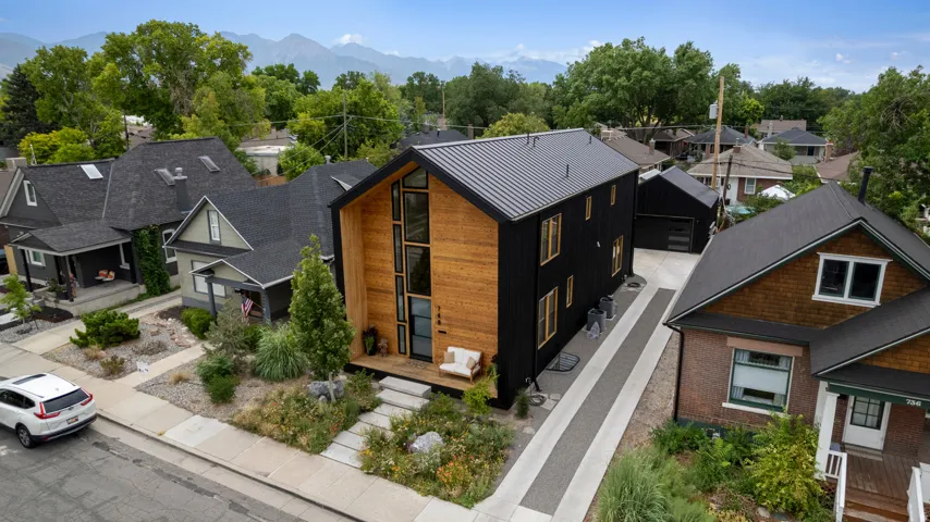 Contemporary residence featuring a striking black exterior with vertical wood accents and a dark metal roof