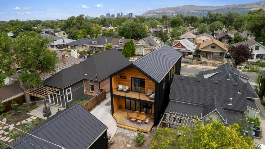 Modern multi-level residence featuring a metal roof, contrasting wood-tone and black siding, and a spacious ground-level deck