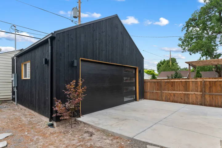 Detached modern accessory structure featuring black vertical siding and a black garage door with frosted glass panels