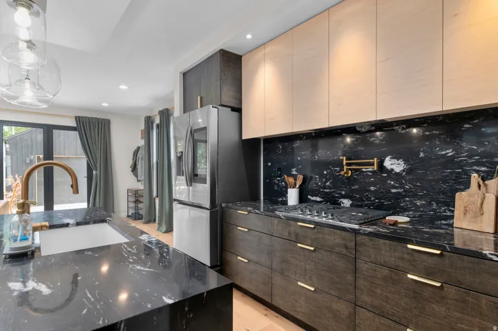 Contemporary kitchen featuring dark countertops with white veining, light wood-finish upper cabinetry, and dark wood-finish lower cabinetry