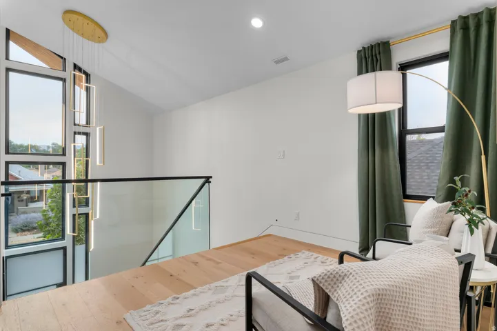 Contemporary living area featuring wood-finish flooring and a minimalist glass railing