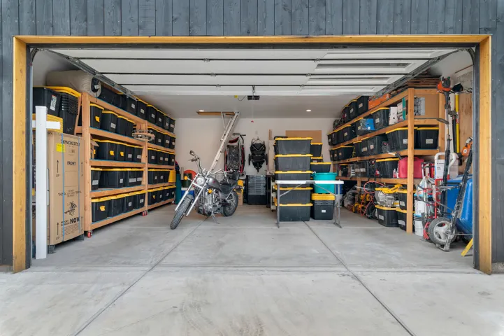 Garage interior featuring a concrete floor, extensive built-in wooden shelving, and track lighting