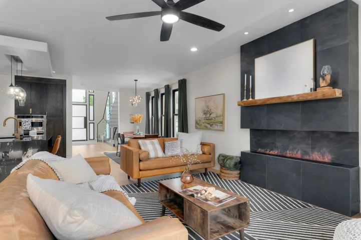 Open-concept living area featuring a modern fireplace with a dark tile surround and a wood mantel