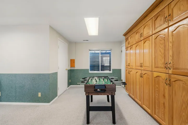 Game area with storage room on left and built-in cabinetry on right,