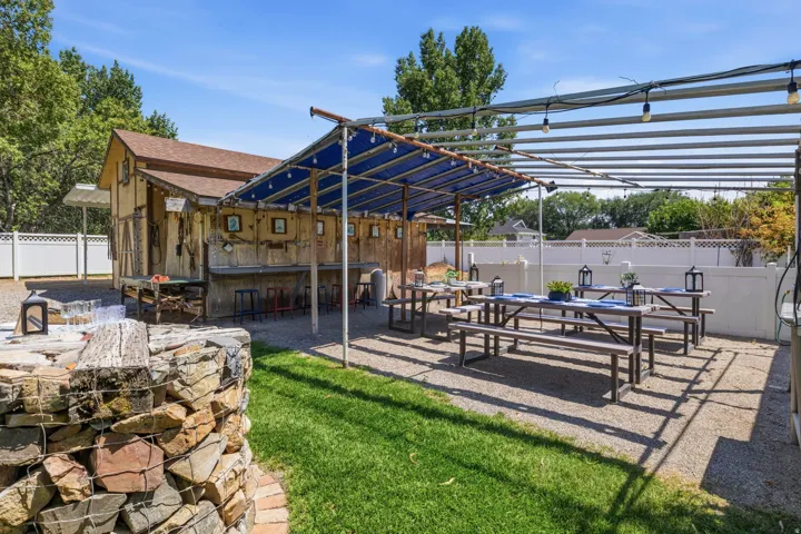 Outdoor entertainment space featuring a gravel patio, built-in bar seating, covered pergola and al fresco dining area.