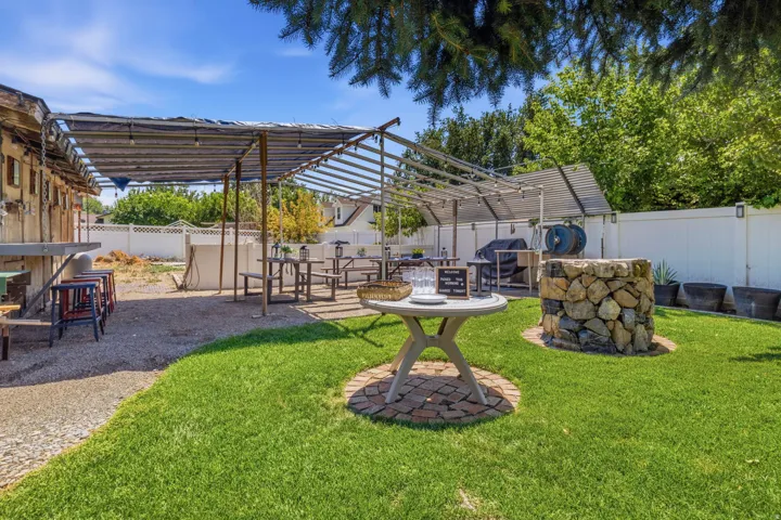 Outdoor entertaining area featuring a gravel patio, built-in bar seating, covered pergola and al fresco dining area.